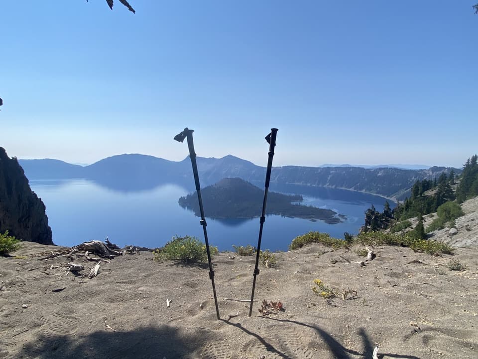 Trekking poles planted in the rim sand above Crater Lake