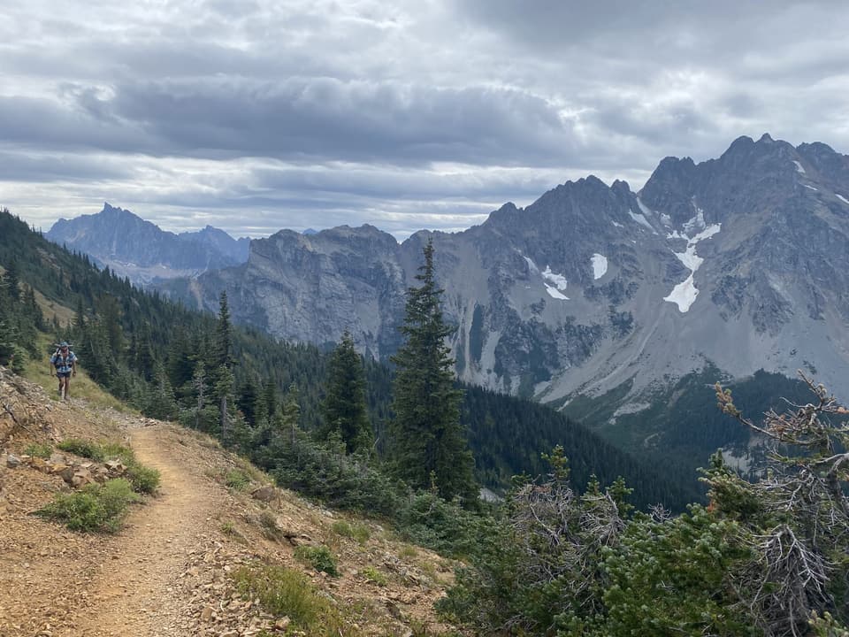 A jagged North Cascades ridge with a hiker on the trail